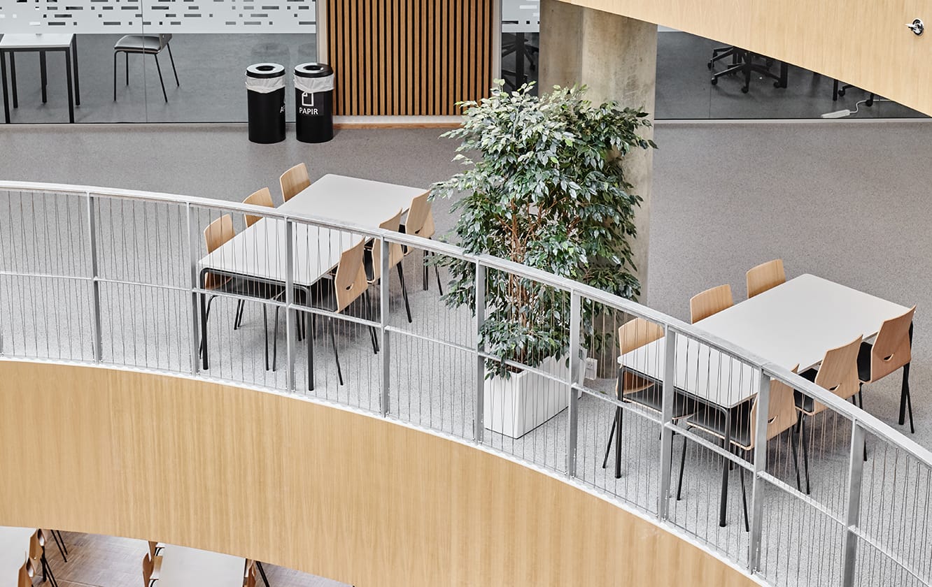 A spiral staircase with office tables and office desk chairs in an office building.