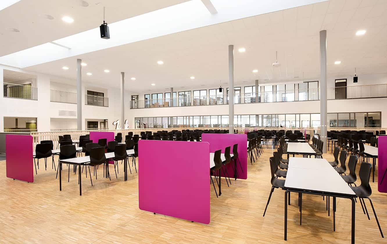 A large room with canteen furniture such as tables and chairs in it.