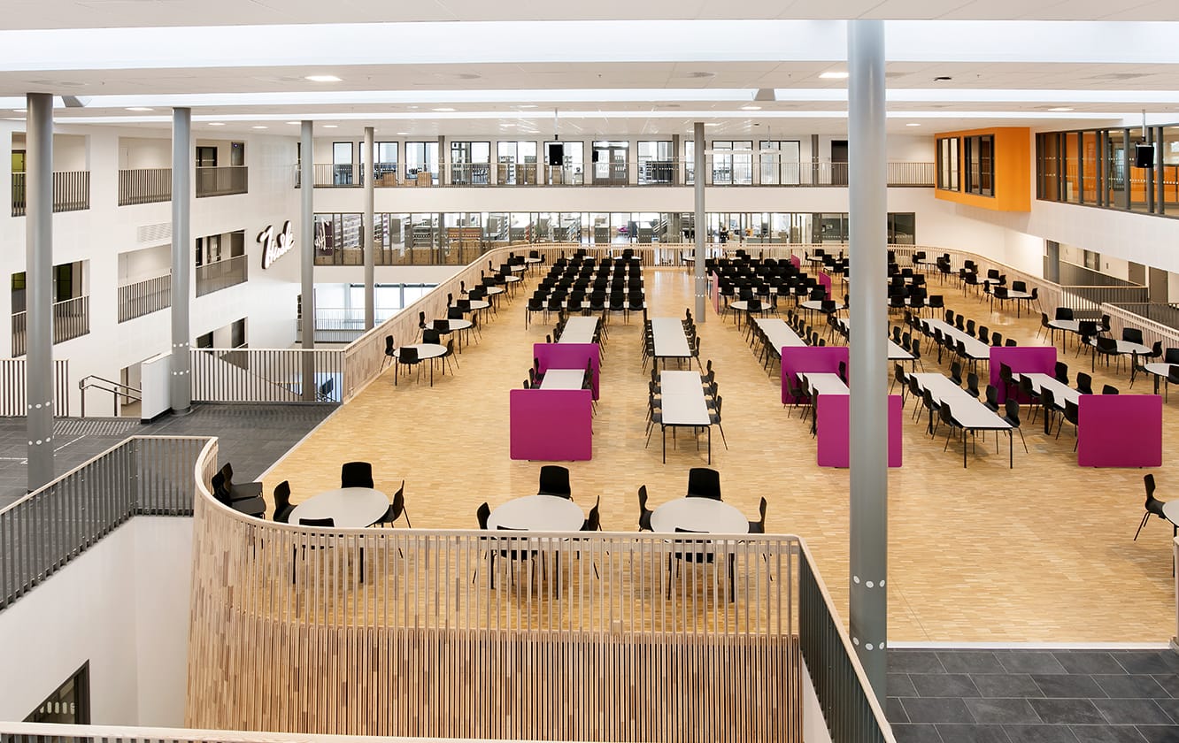 A large room with canteen furniture such as tables and chairs in it.