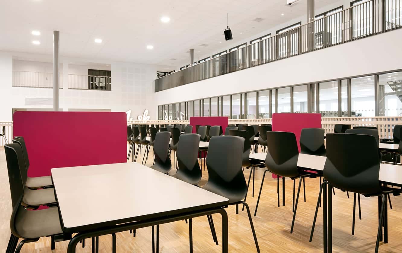 A large room with canteen furniture such as tables and chairs in it.