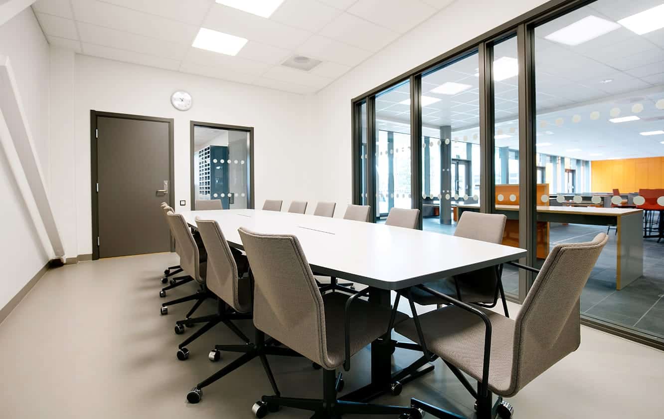 A conference room with a large conference table and office desk chairs.