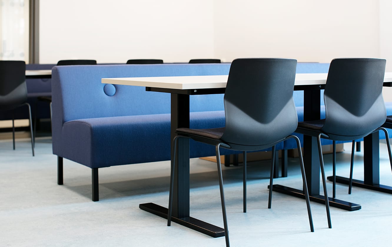 A group of chairs and office tables in a room with a blue office sofa.