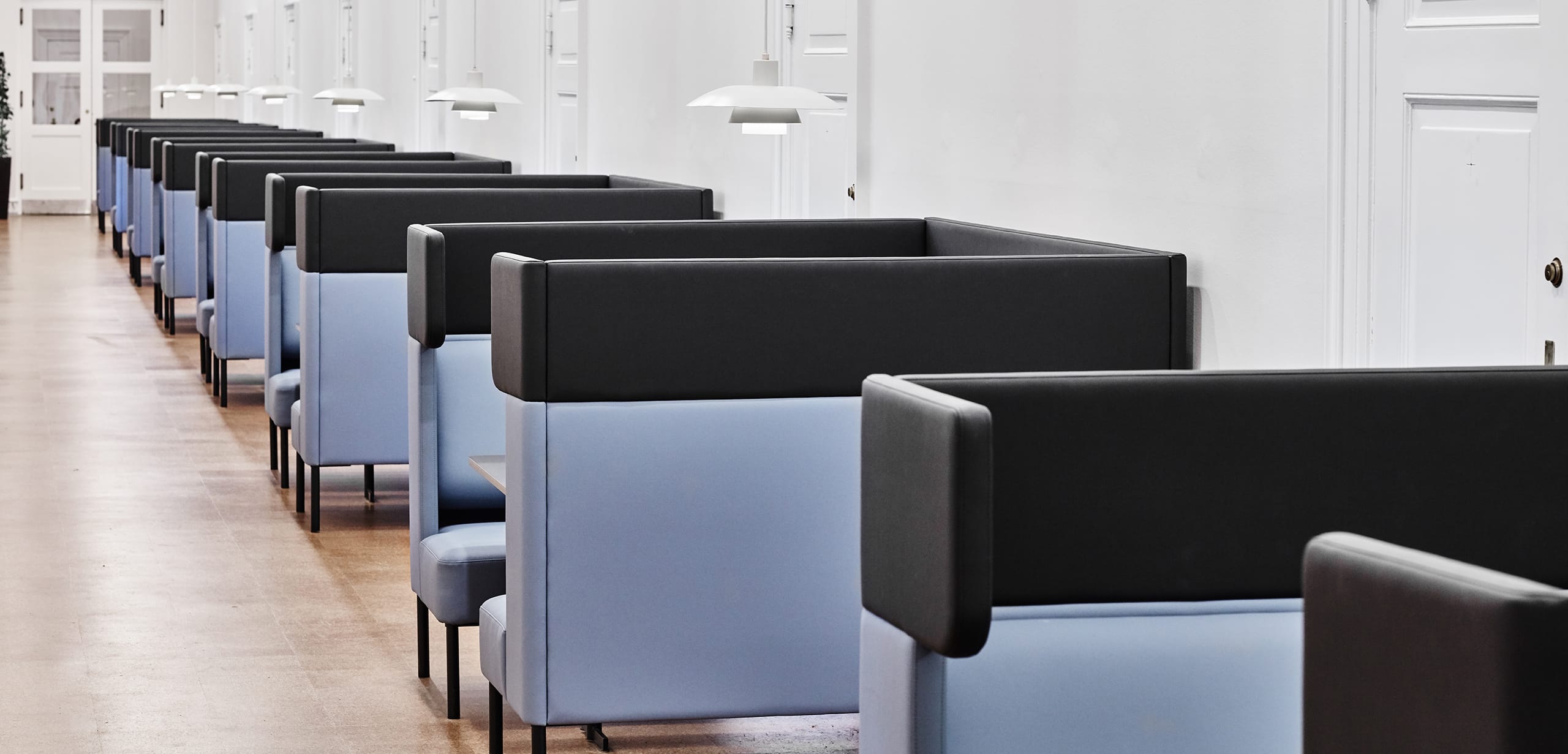 A row of blue and black office work booths in a hallway.