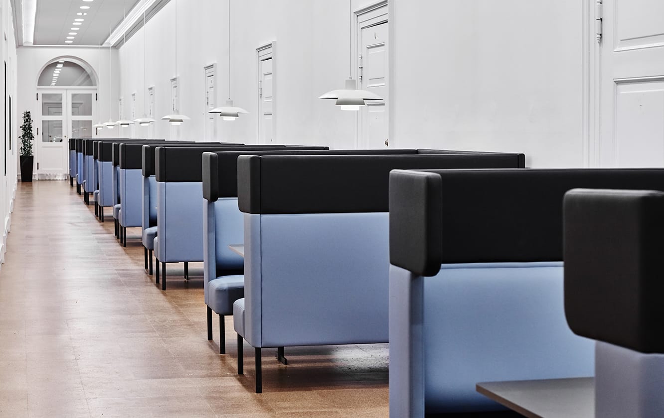 A row of blue and black office work booths in a hallway.