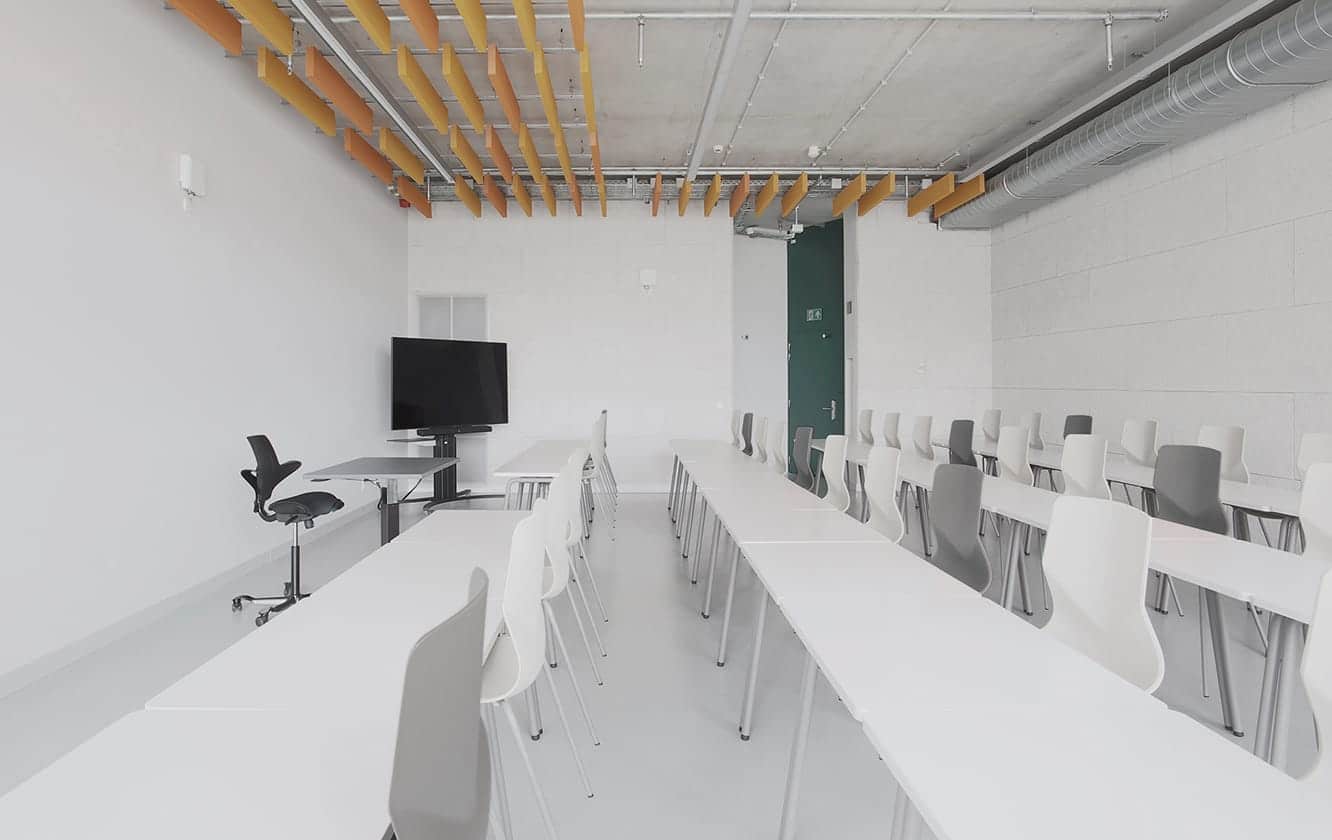 A group of office desk chairs and office tables in a lecture hall with a TV