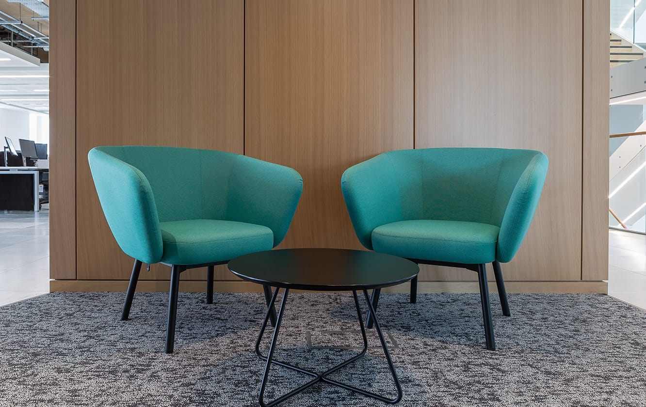 Two lounge chairs for offices in an office with a table in the middle.