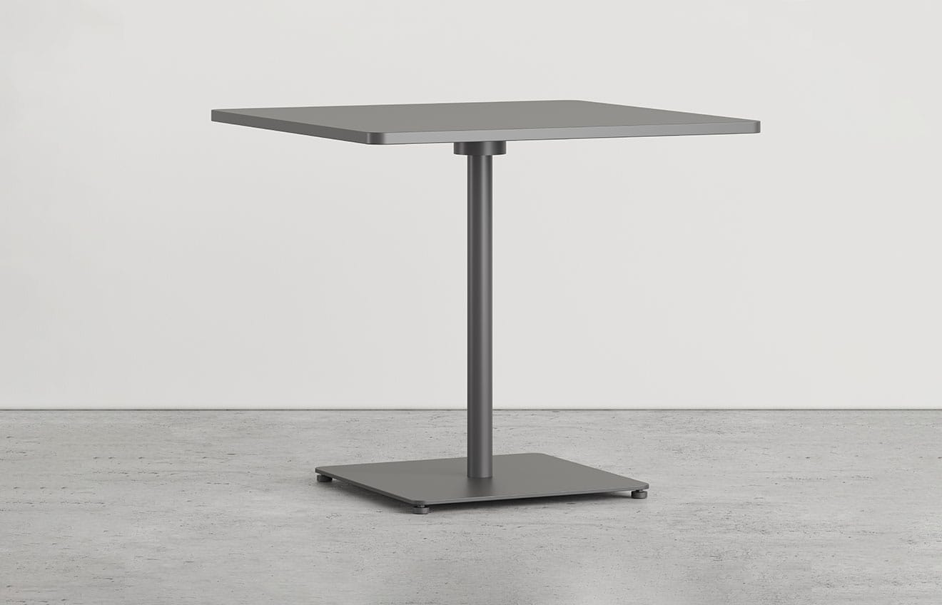 A square pedestal table with a metal base on a concrete floor.