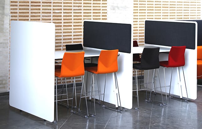 A group of desk workstations with acoustic panels on the side panels in a conference room.