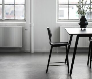 A dining table with two black counter height chairs in front of a window.