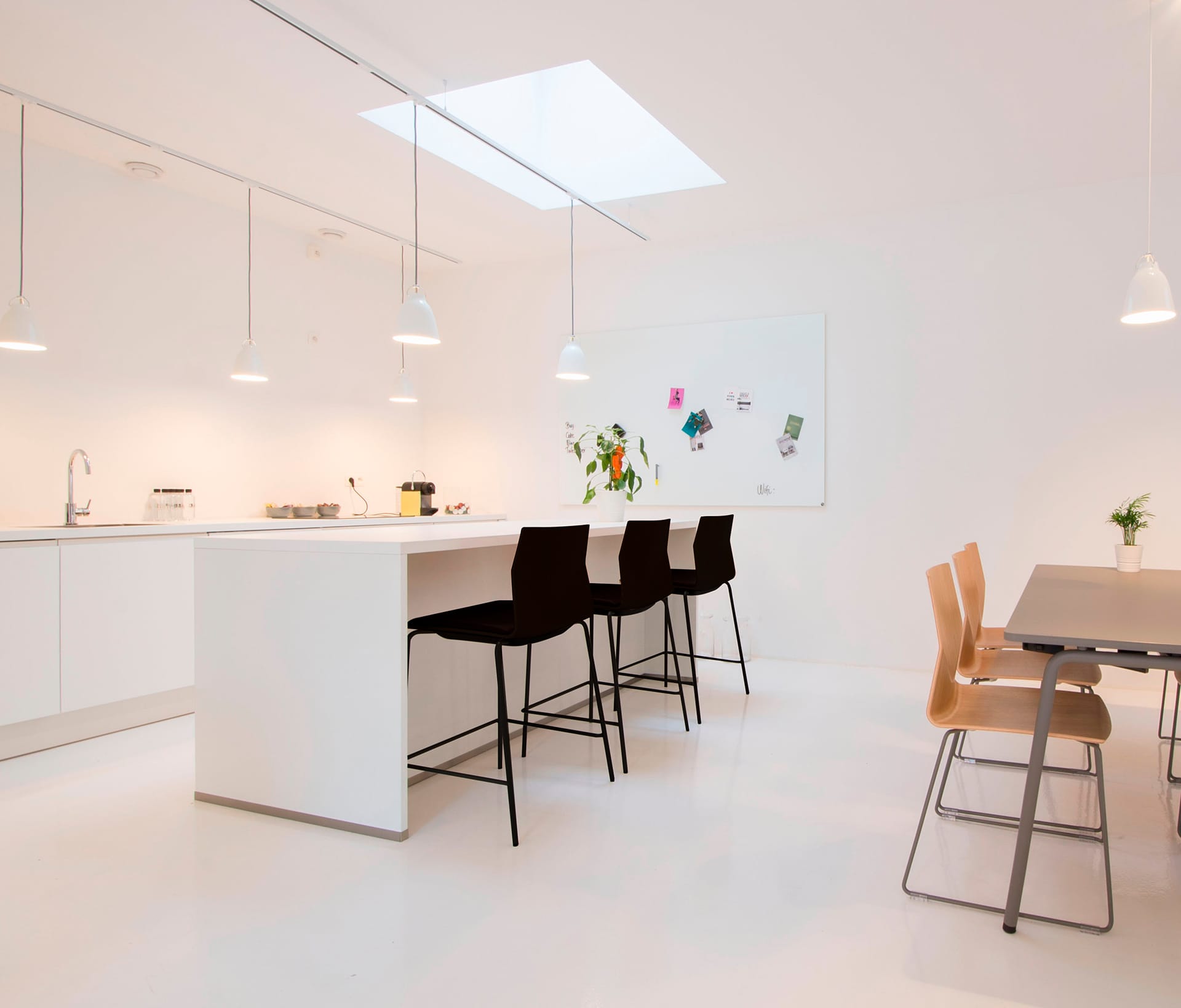 A white kitchen with counter height tables and chairs.