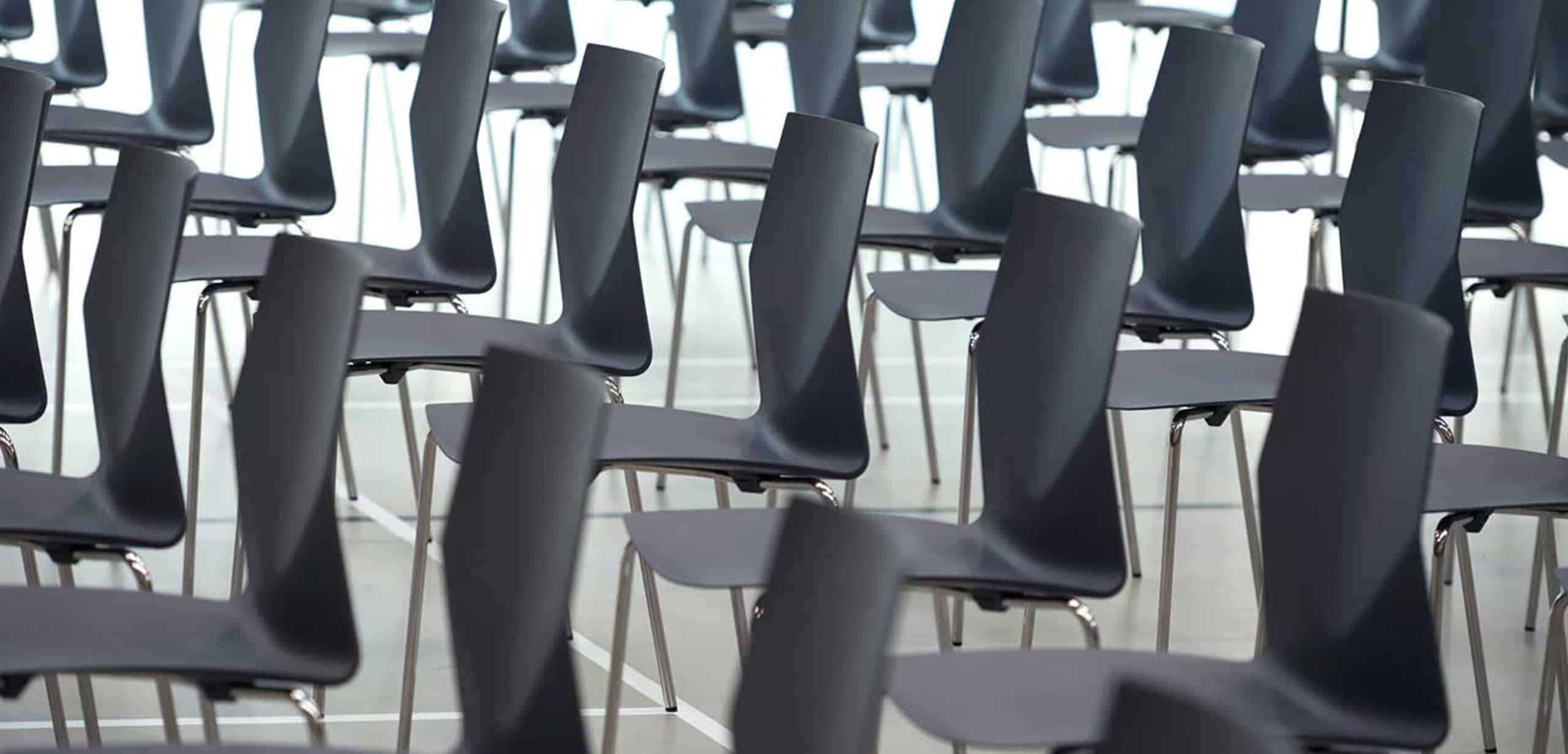 A row of black chairs on a tennis court.