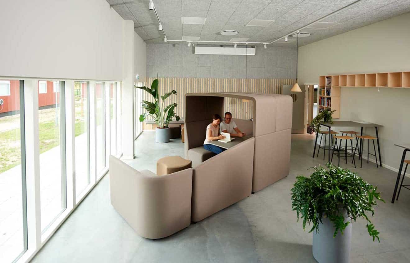 Two people sitting at a table in an office work booth in an office.