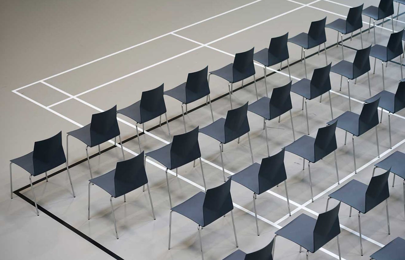 A row of black chairs on a tennis court.