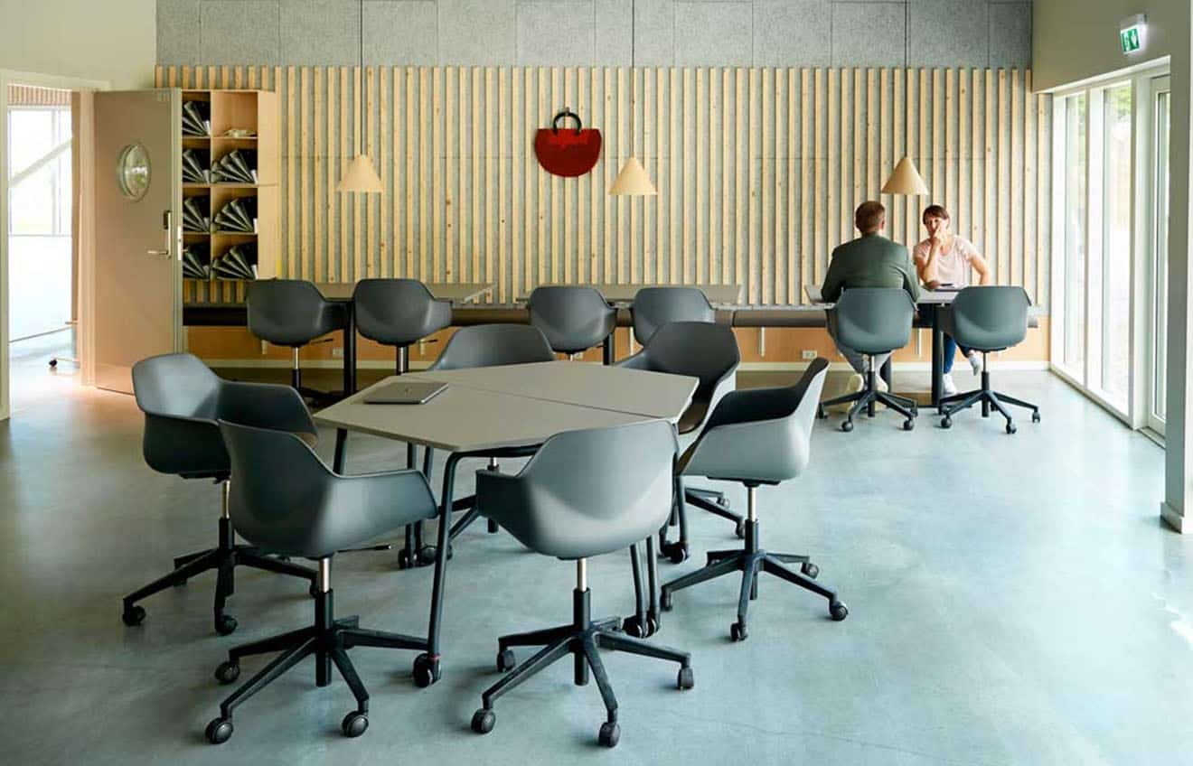 A group of people sitting around a office tables in an office.