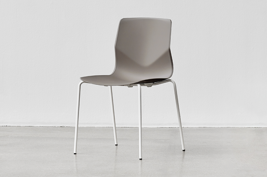 A grey plastic chair against a white wall.