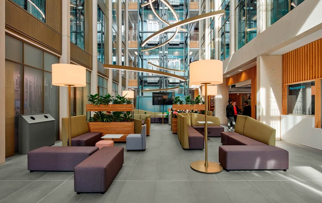 The lobby of a modern office building with office furniture in it.