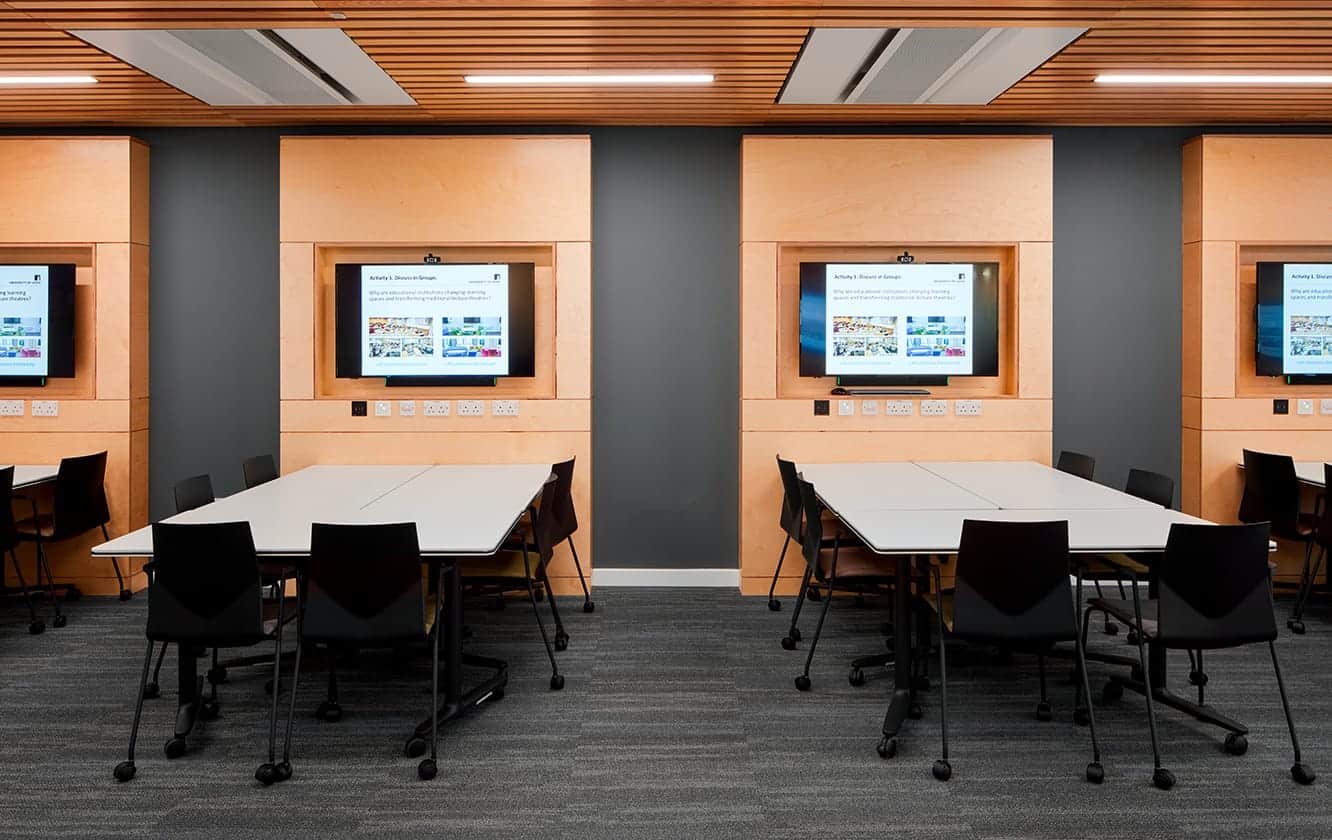 A conference room with tables and tv screens.