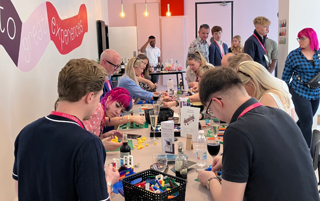 A group of people at a table making legos at Clerkenwell design week.