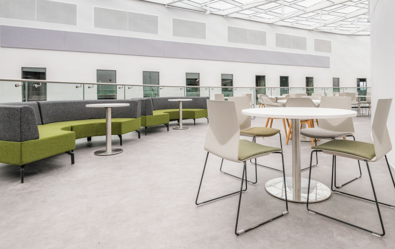A modern office full of Ocee and Four Design office furniture with tables and chairs and a glass roof at the University of Sheffield