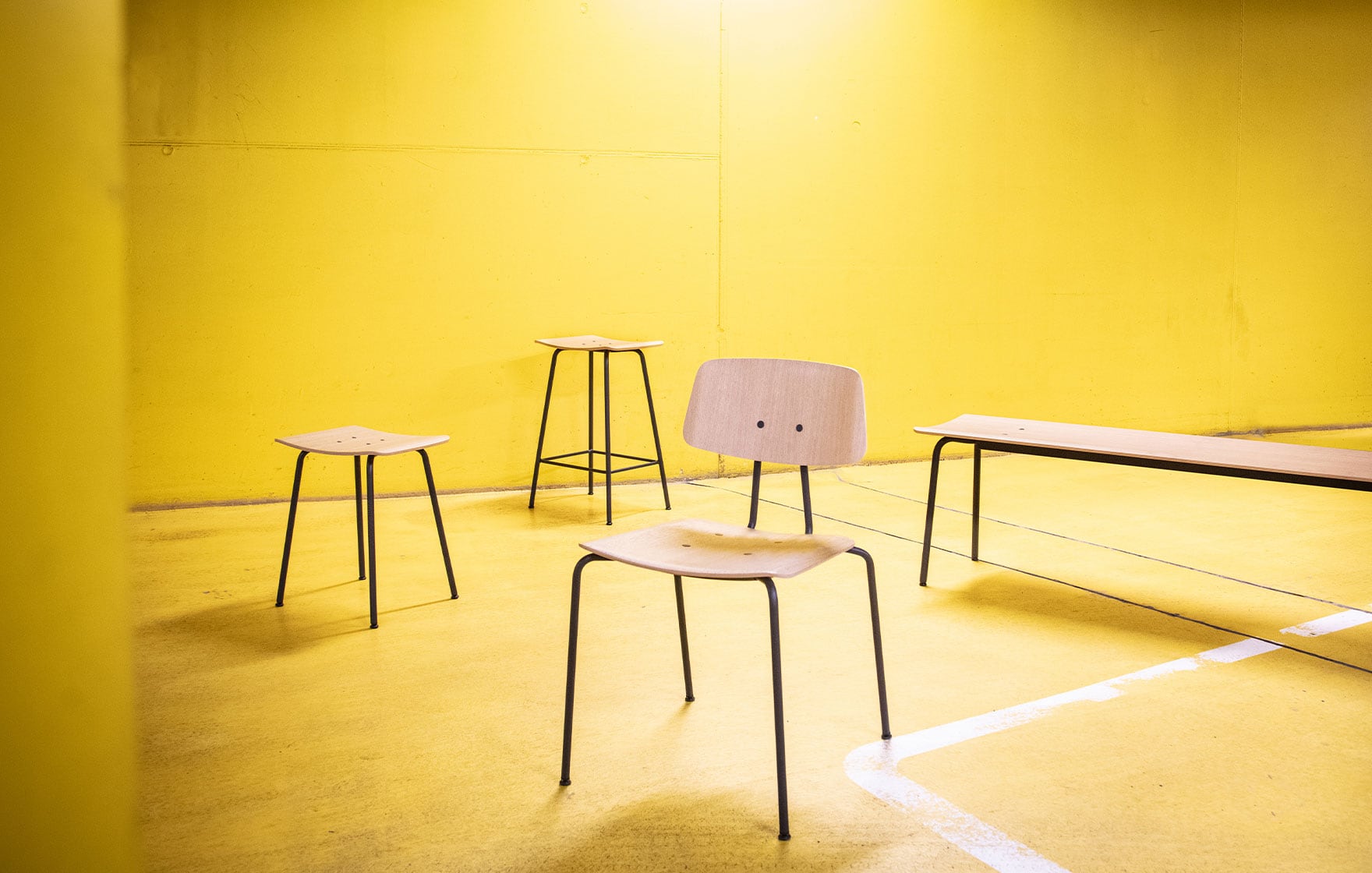 A group of Ocee and Four design office furniture including chairs and a bench in a room with yellow walls.