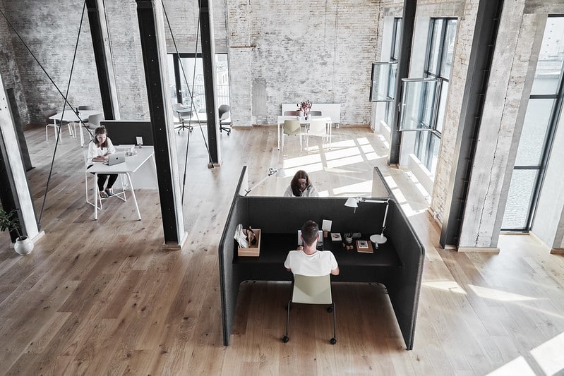 A group of people sitting at desks in an office with Acoustic office screen dividers.