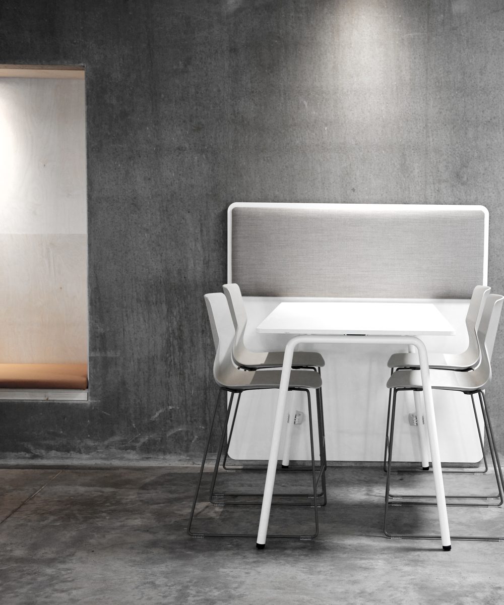 A white FourReal 90 table wiht FourSure 44 chairs against a concrete wall
