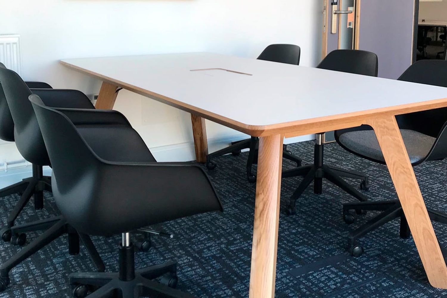 A conference table with wooden legs and chairs in an office.