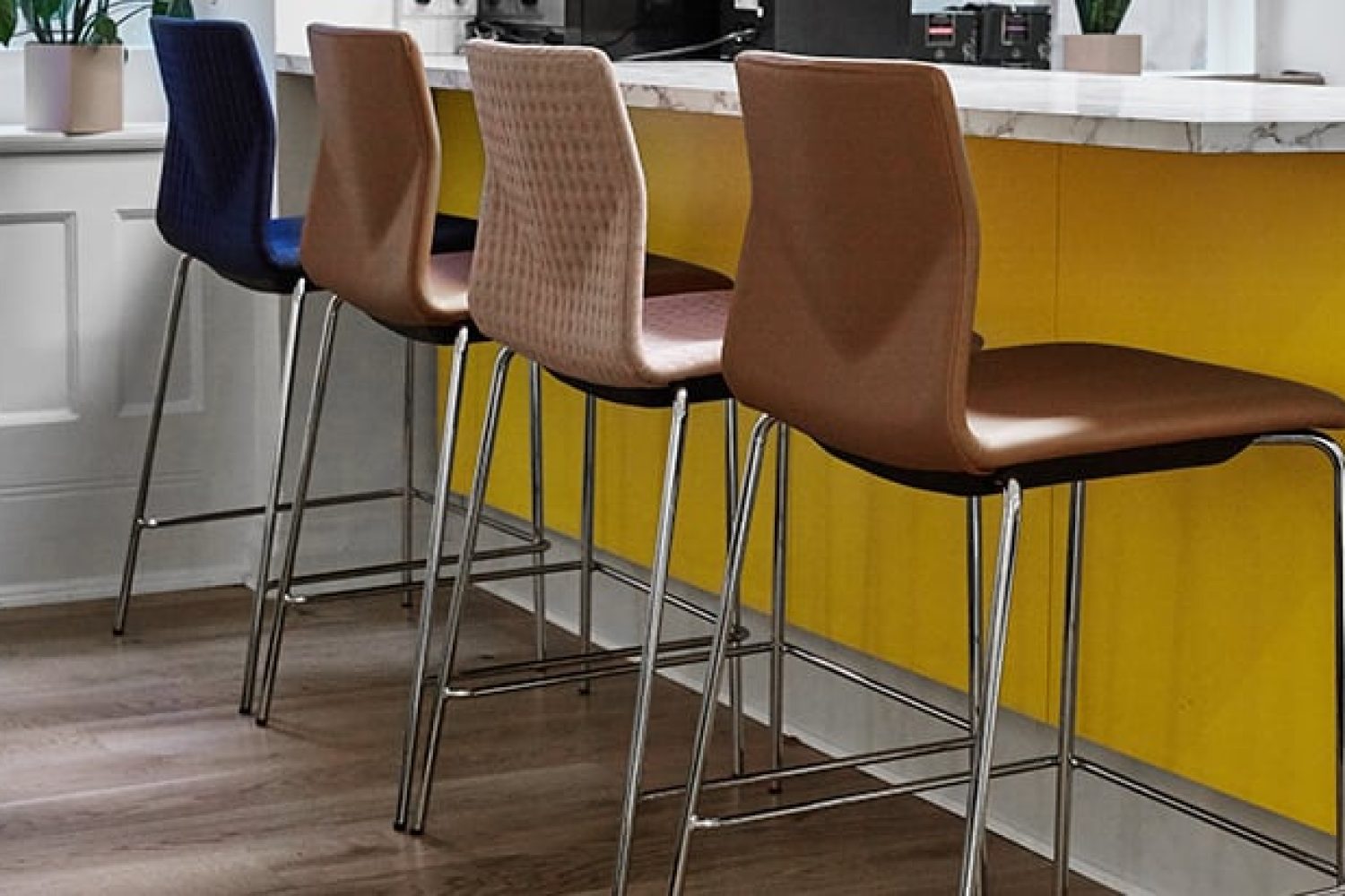 Four counter chairs in a kitchen with yellow walls.