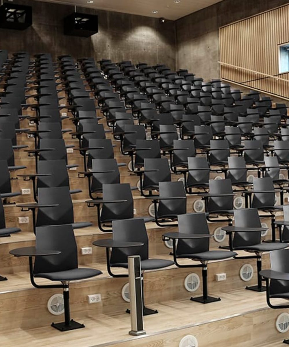 A large auditorium with rows of black chairs.