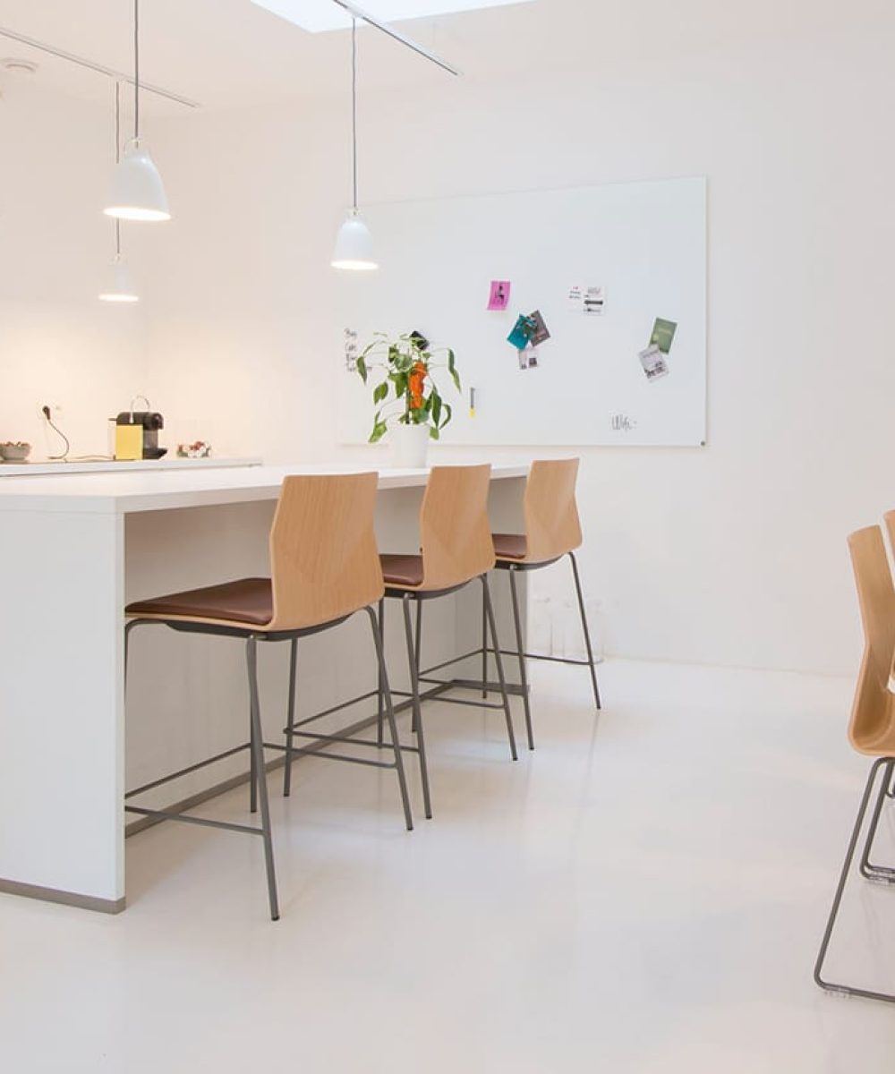 A white kitchen with standing height tables and counter chairs
