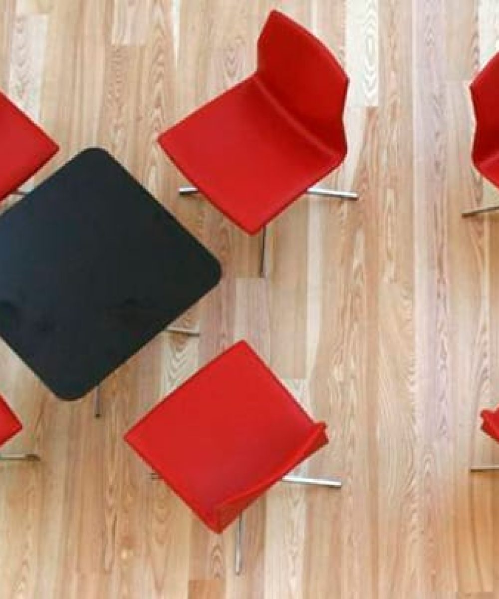 A group of red chairs on a wooden floor.