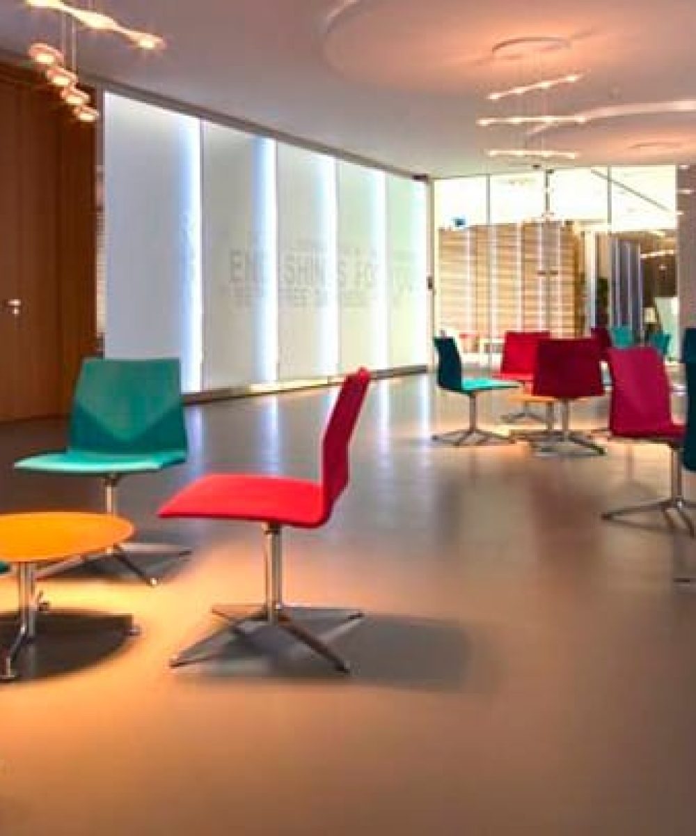 A lobby with colourful chairs and a glass wall.