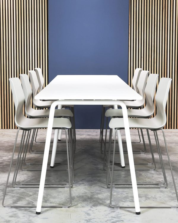 A white table and counter chairs in front of a wooden wall.