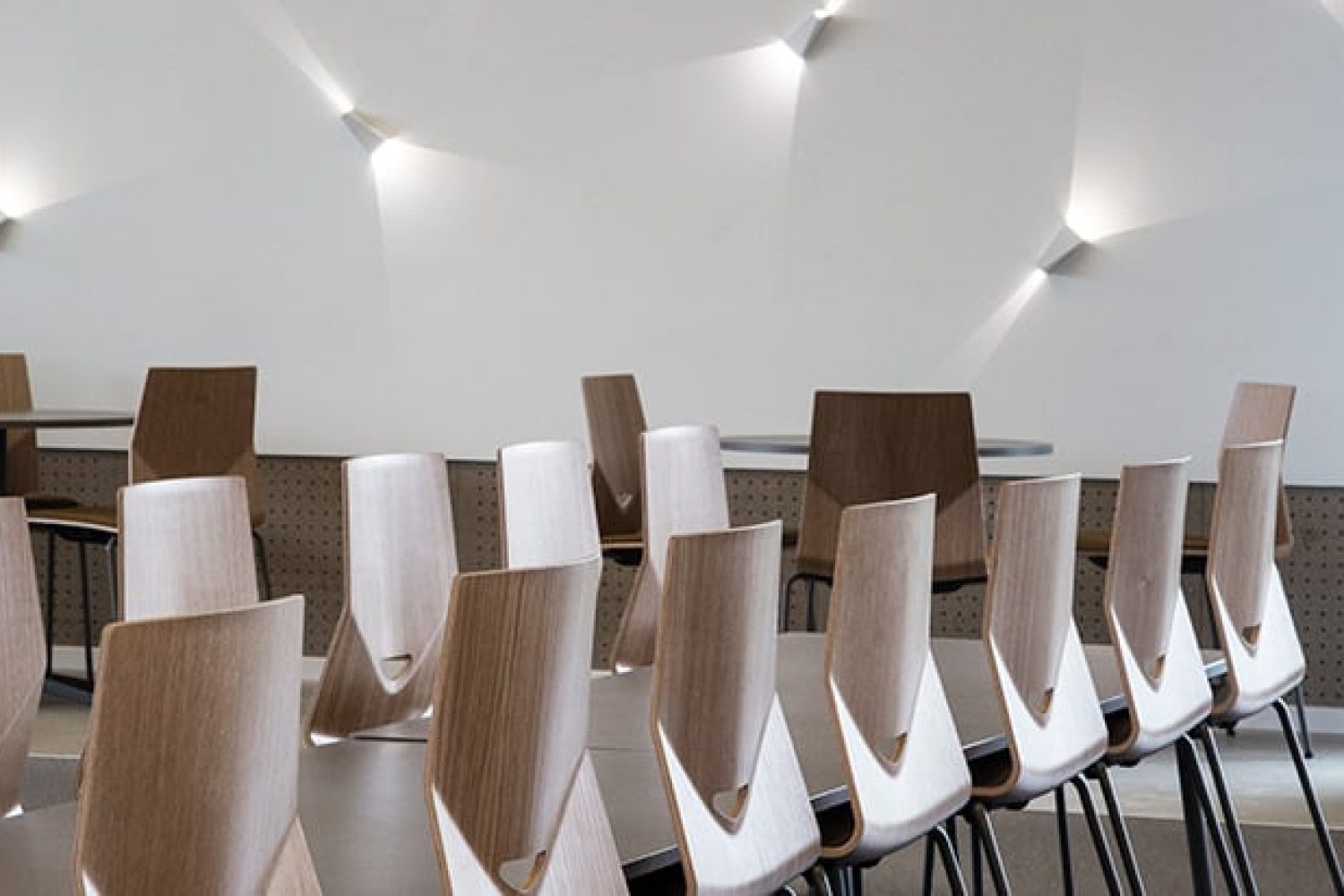 A row of wooden light weight office chairs in a conference room.