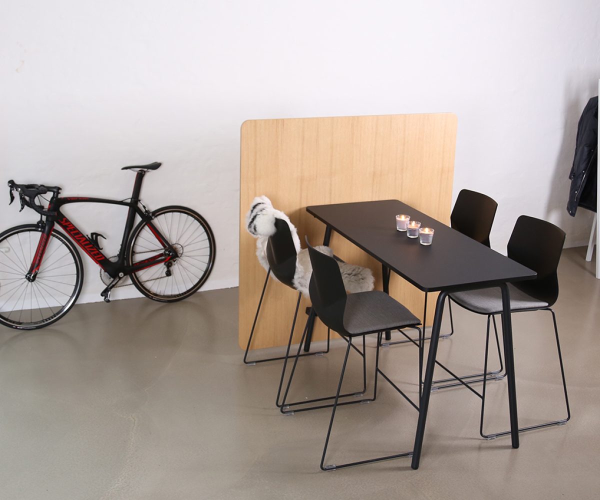 A standing height table and counter chairs with a bicycle parked in front of it.