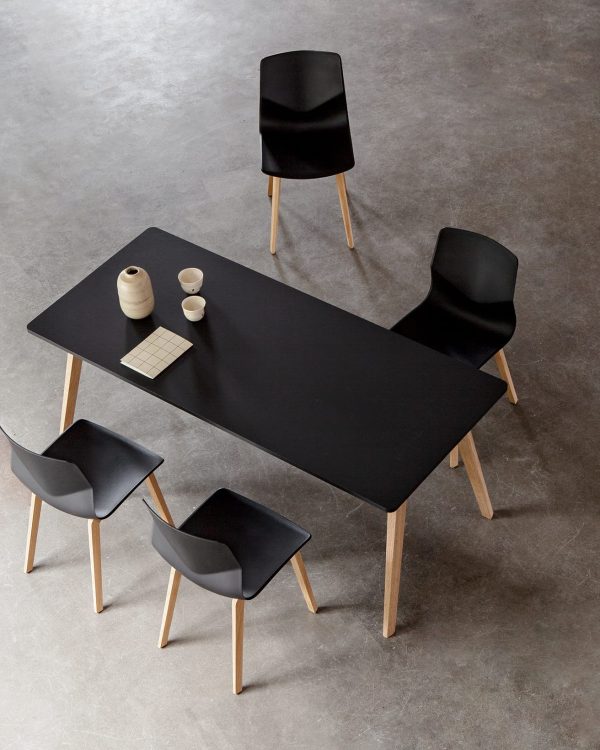 A black dining table with four black chairs.