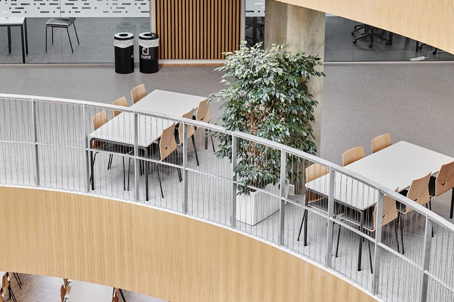 A spiral staircase with office tables and office desk chairs in an office building.