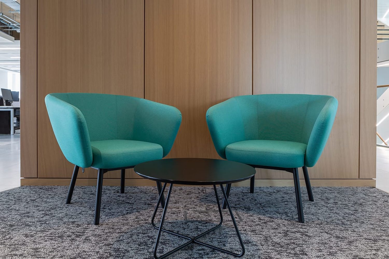 Two lounge chairs for offices in an office with a table in the middle.