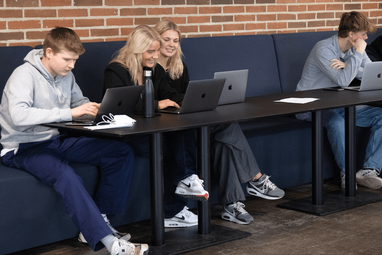 A group of people sitting at desk workstations using laptops.
