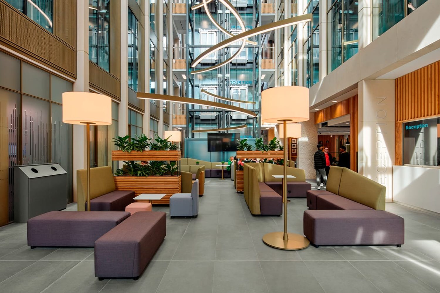 The lobby of a modern office building with office furniture in it.