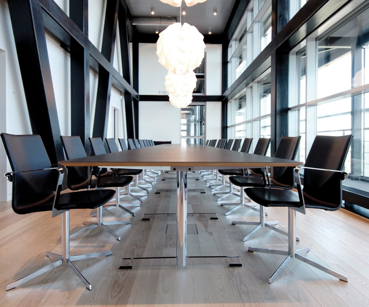A long black conference table with black office desk chairs.