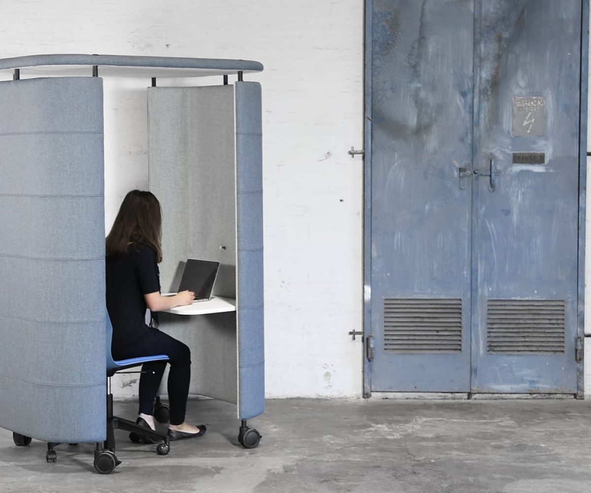blue office work booth with woman on laptop