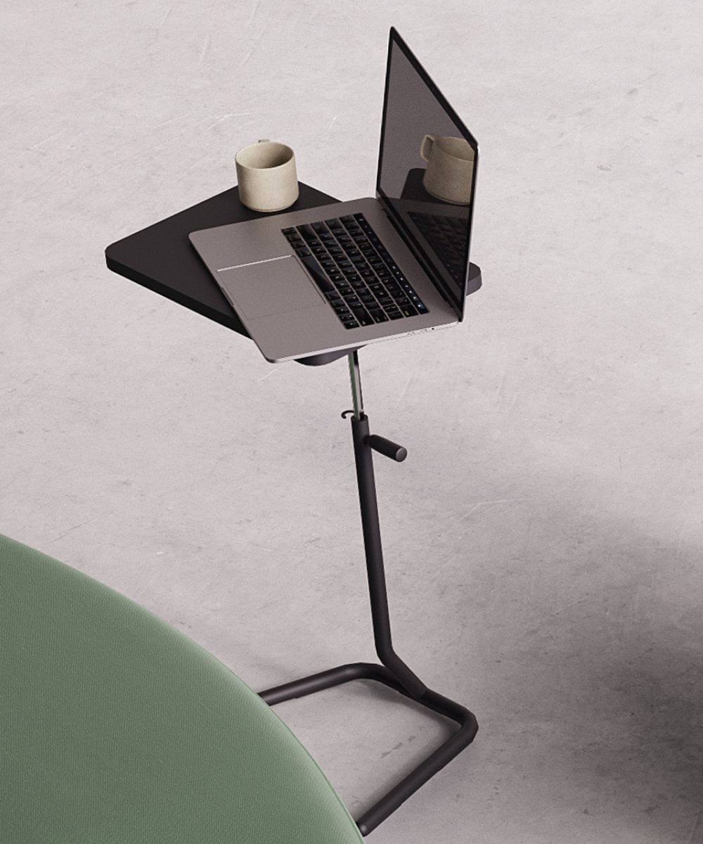 A laptop on an Y-table adjustable height work table next to a green couch.